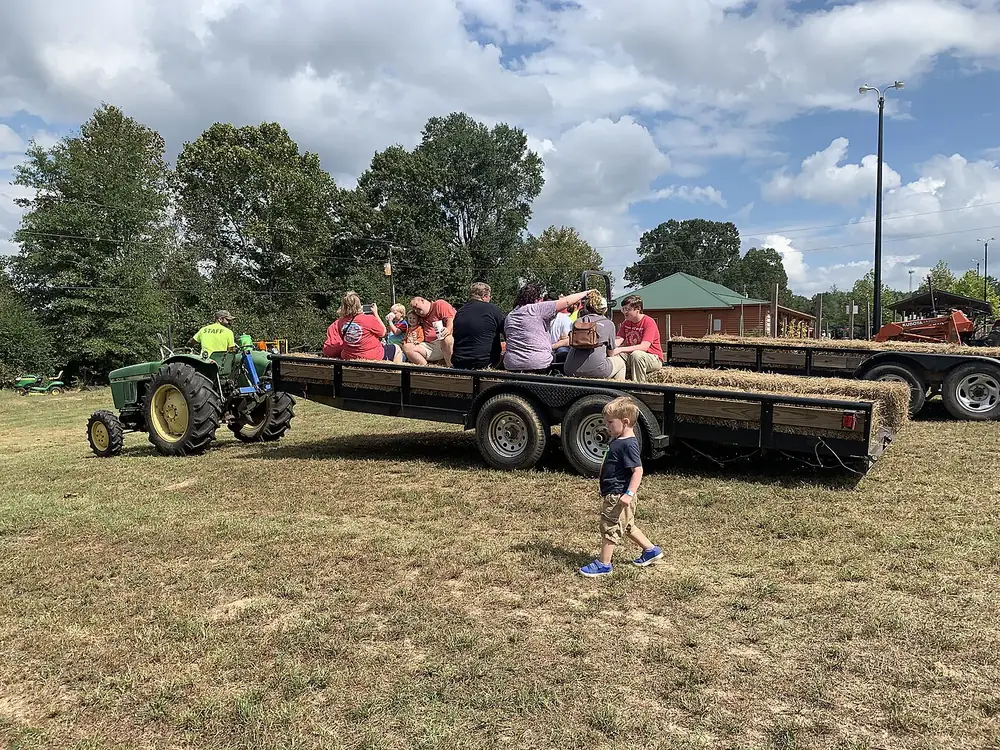 A tractor pulling a hay wagon full of families across a farm field